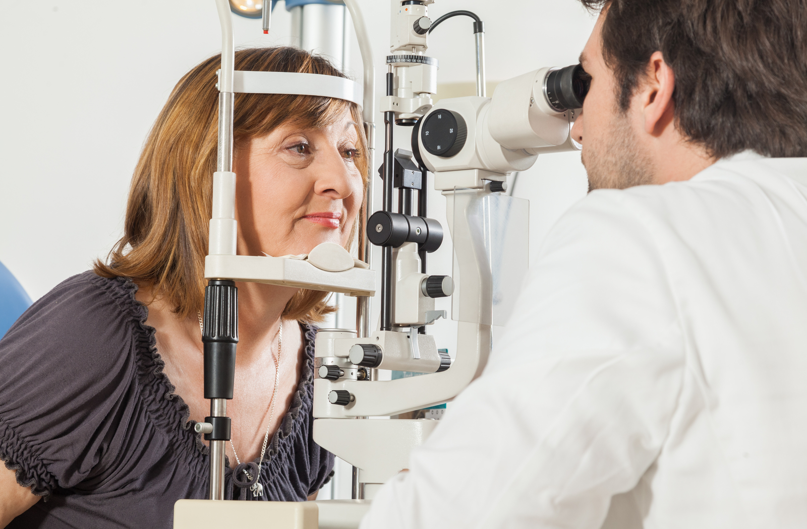 Female optometrist looks at a young female patient's eyes during an examintion with a slit lamp machine.