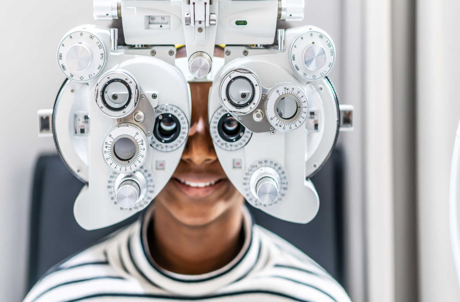 A young boy smiling while looking through a phoropter.