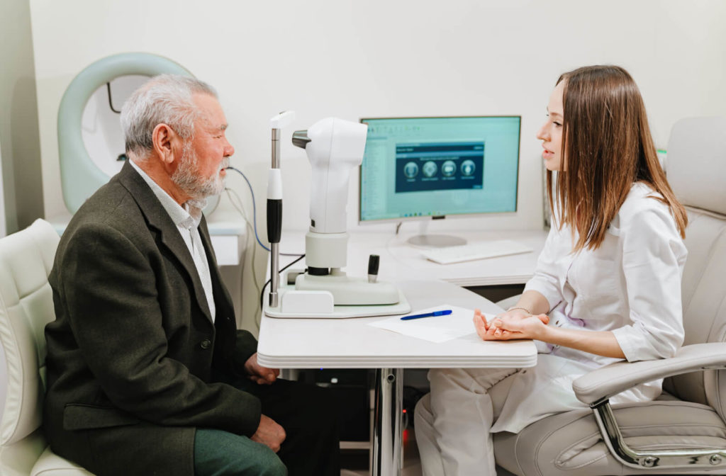 A female optician is interviewing an elderly male patient during an eye exam at the optical clinic.