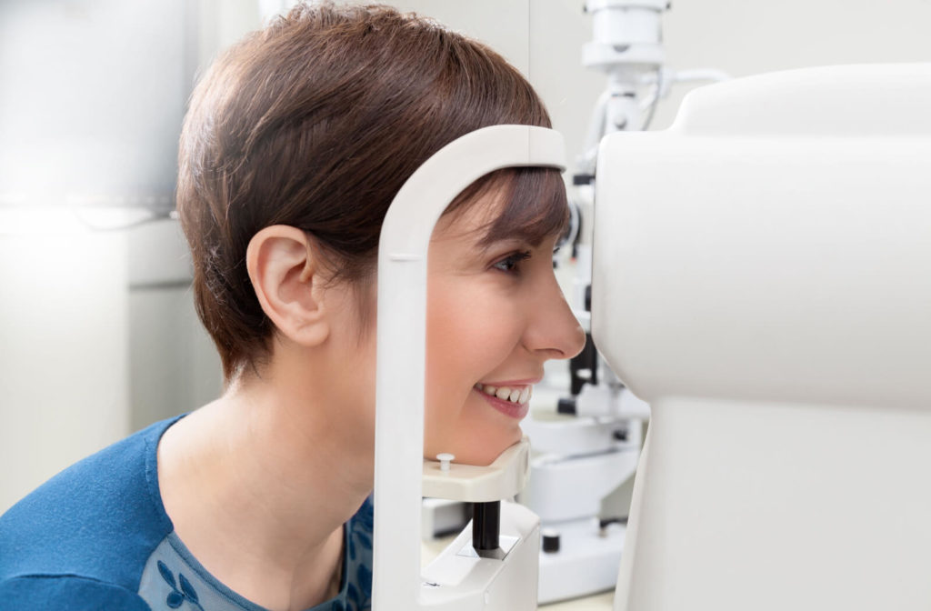 A female young adult is looking through an autorefraction machine to measure her prescription for eyeglasses or contact lenses.