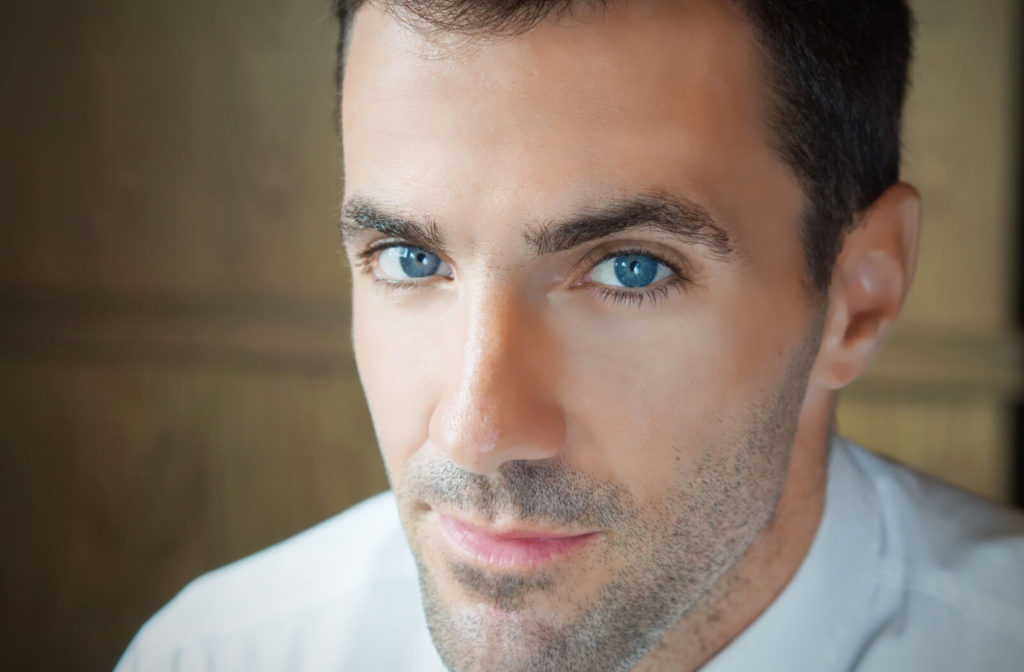 A close-up of a man with blue eyes looking directly at the camera