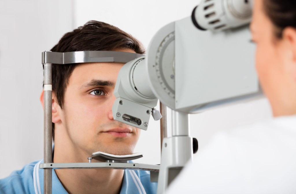 A man sitting in an optometrist's office and looking into a machine that tests his vision