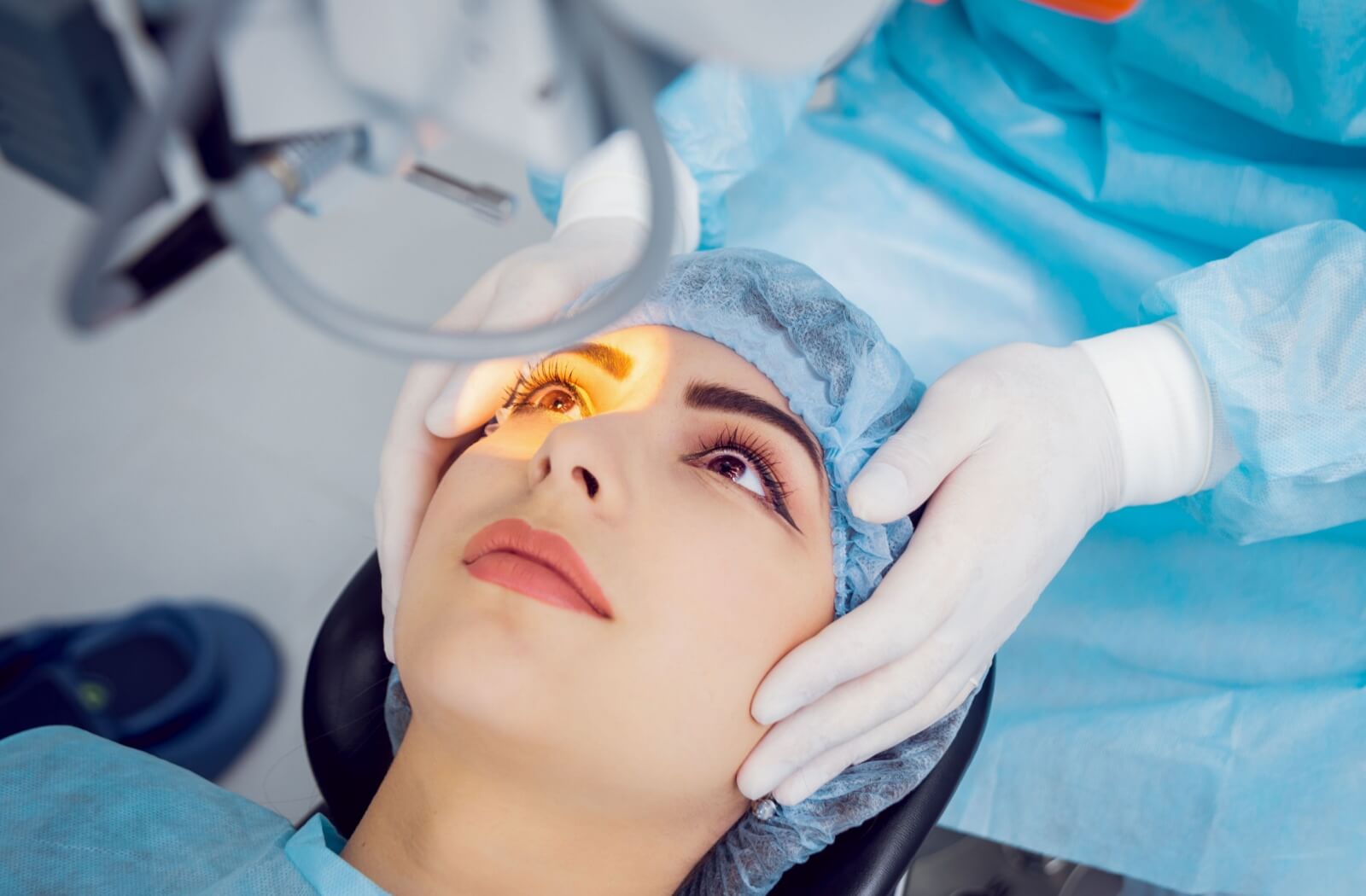 Close up of a young woman's face looking into a light as her eye doctor prepares her for laser eye surgery.