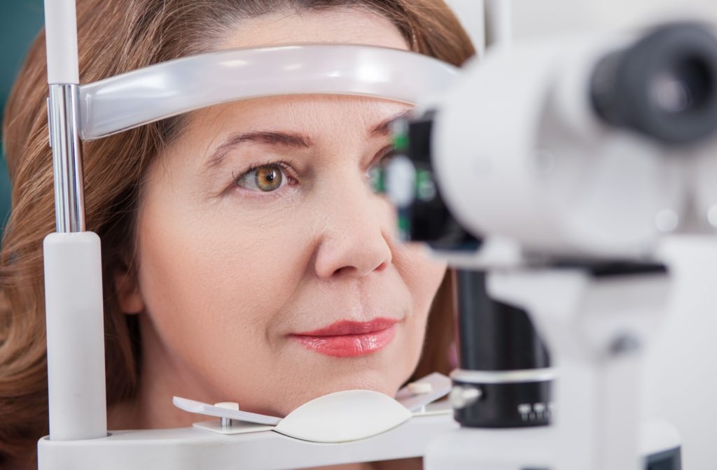 An adult patient sits calmly for a slit lamp exam at their eye doctor's office.