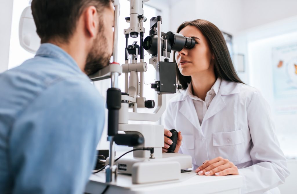 An optometrist checking her patient's eyes during an eye exam to determine if he qualifies for LASIK.