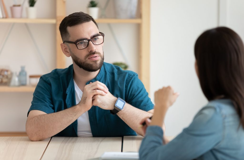 A person wearing glasses faces another person across the table while they discuss their vision.