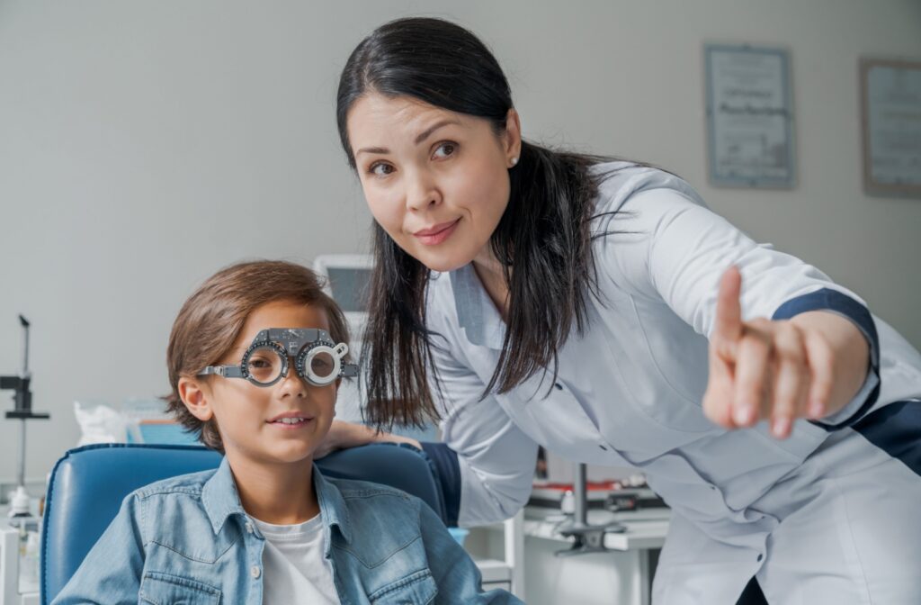 Optometrist pointing at something next to a young patient wearing a diagnostic eye tool.