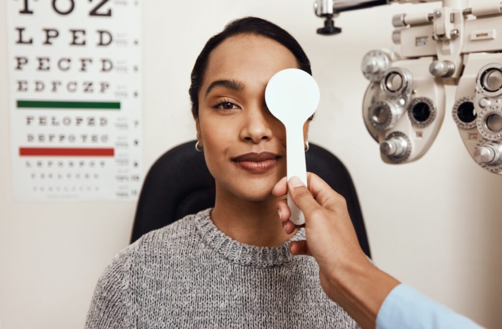 Optometrist holding a vision testing tool during an eye exam, covering the patients eye.