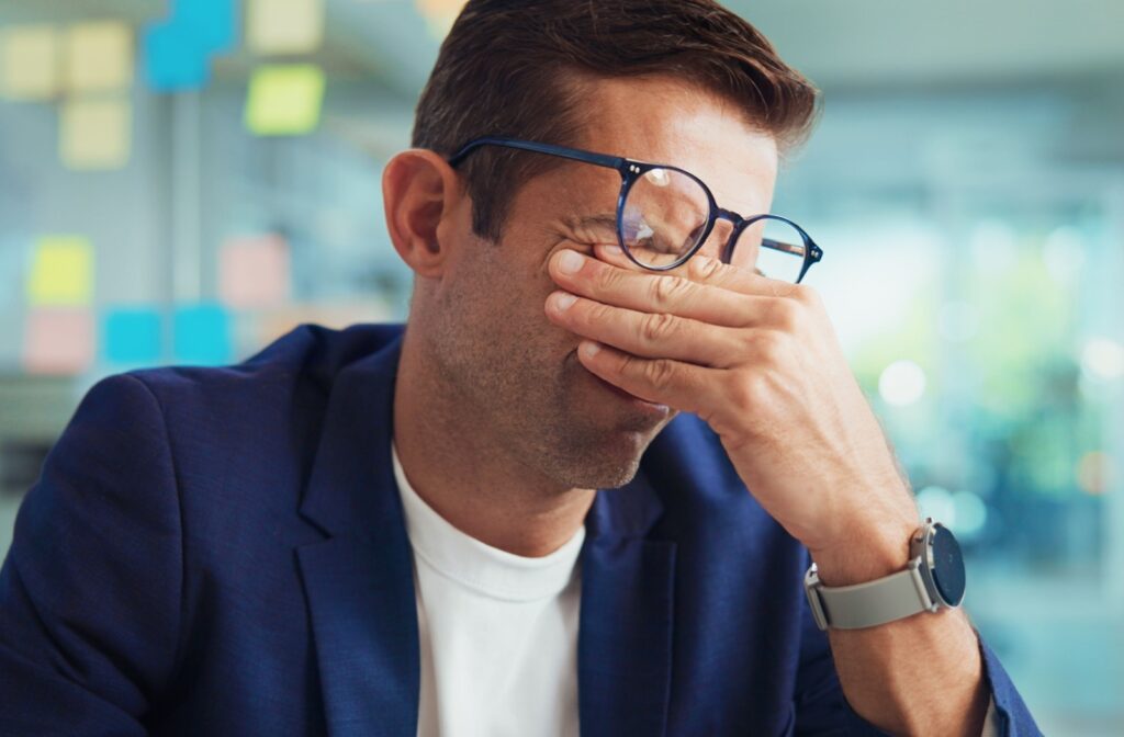 A person rubbing their eyes under their glasses because their prescription is out of date.