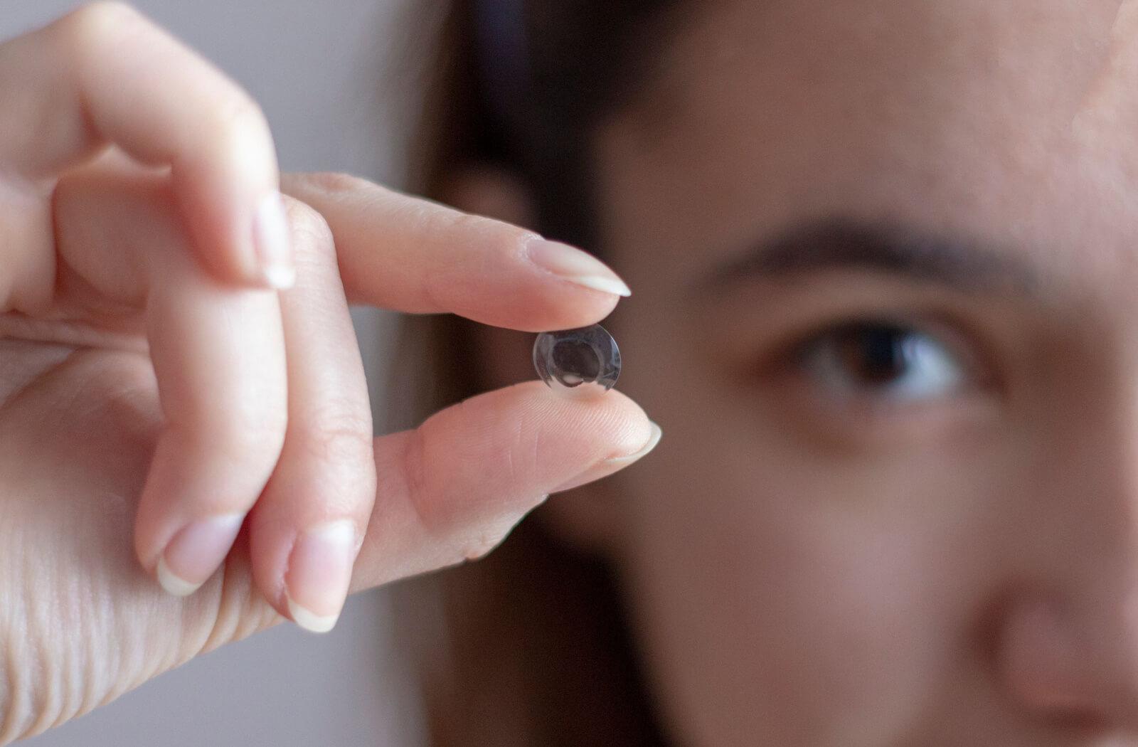 A person holding an ortho-k contact lens for myopia control.